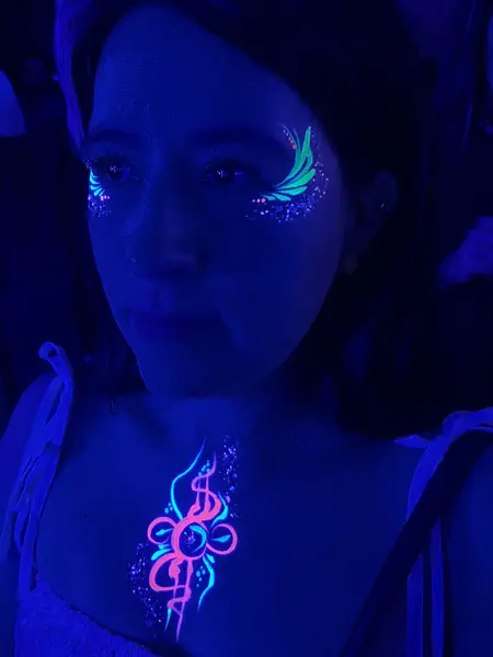Maquillaje flúor rosado en el cuello y detalle en el ojo de una mujer
