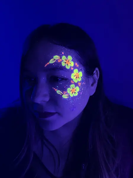 Maquillaje flúor de flores en la mejilla de una mujer