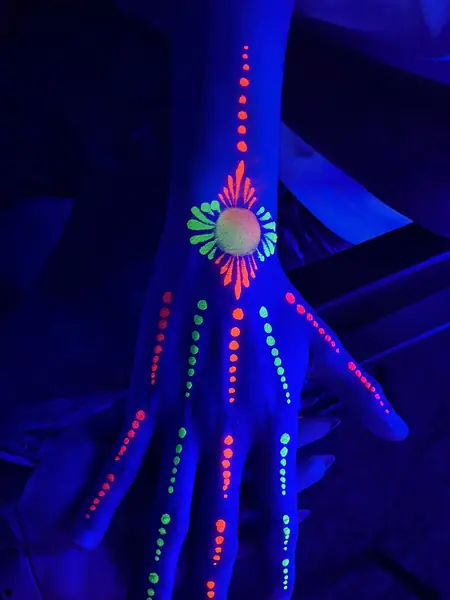 Maquillaje flúor de mandala y puntos en la mano
