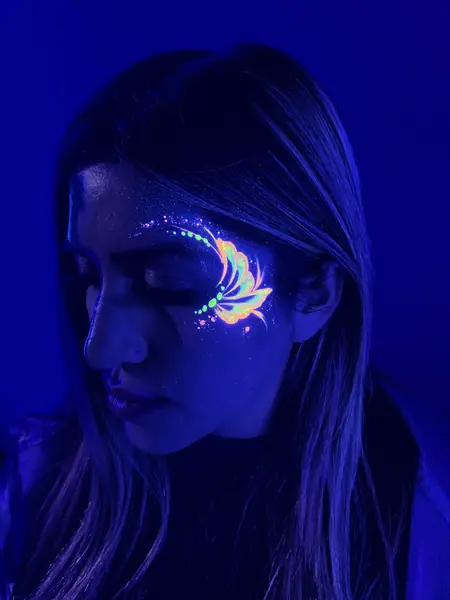 Maquillaje flúor de mariposa en la mejilla de una mujer