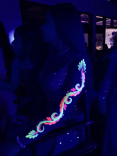 Maquillaje flúor de ondas en el brazo en una fiesta de noche