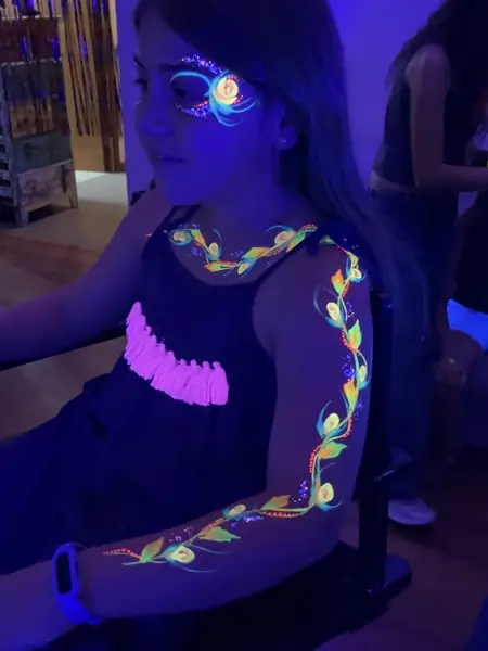 Pinta caritas flúor en el brazo y el ojo de una niña