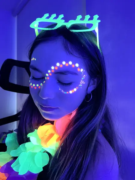 Pinta caritas flúor de puntos de colores en el rostro de una adolescente