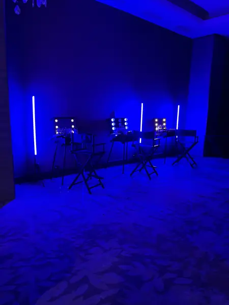 Tres stands de maquillaje montados con luz ultravioleta en un salón de eventos