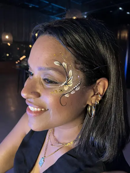 Maquillaje glitter dorado y blanco en el ojo y la sien de una mujer en una fiesta