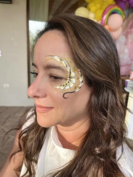Maquillaje glitter de flor blanca y dorada en el ojo