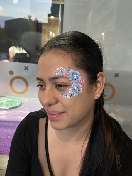 Maquillaje glitter de flores celestes junto al ojo