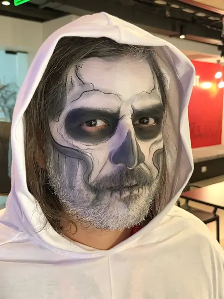 Maquillaje de calavera con grietas en un hombre con capucha blanca