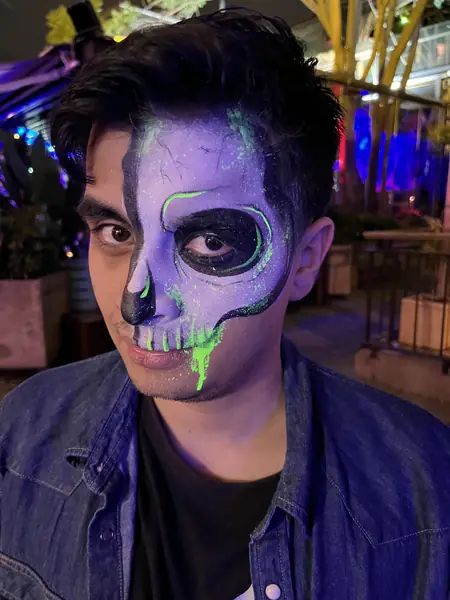 Maquillaje de media calavera con detalles verde neón en una fiesta de noche
