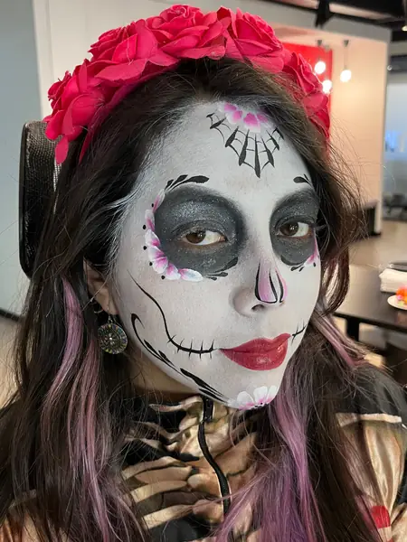Maquillaje de catrina con corona de flores rojas en una fiesta de Halloween de oficina