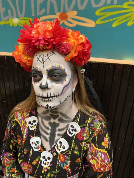 Maquillaje de catrina con tocado de flores naranjas y rojas