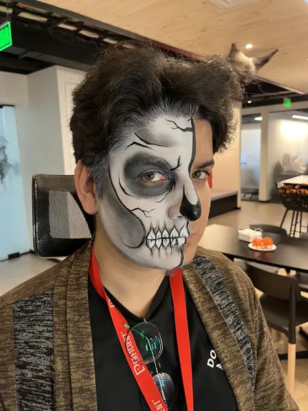 Maquillaje de media calavera en el rostro de un hombre, Halloween en una oficina