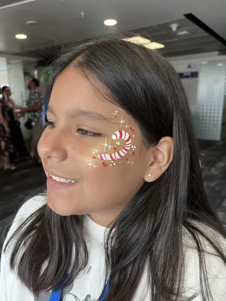 Pinta caritas de bastón de caramelo con brillos en la mejilla de una niña
