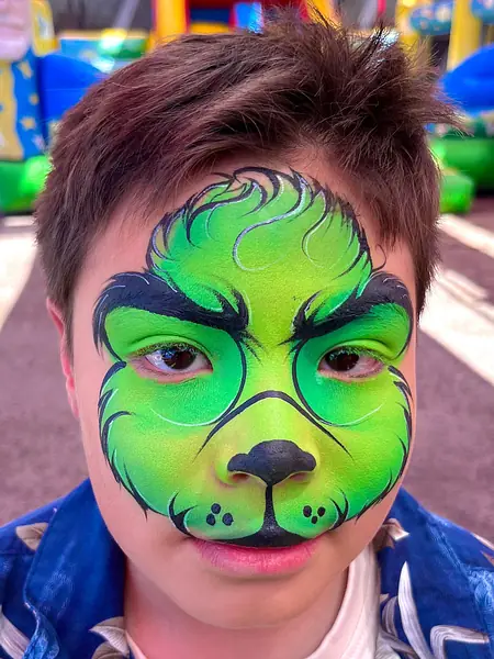 Pinta caritas del Grinch en el rostro completo de un niño, fiesta de Navidad