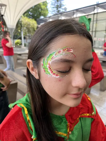 Diseño navideño de hojas verdes y rojas alrededor del ojo de una adolescente