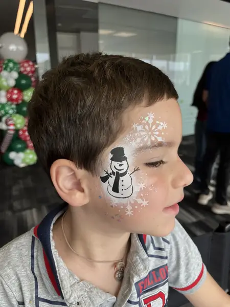 Pinta caritas de mono de nieve con copos en la mejilla de un niño, fiesta de Navidad en una oficina