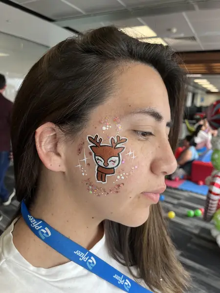 Pinta caritas de reno con brillos en la mejilla de una mujer, fiesta de Navidad de empresa